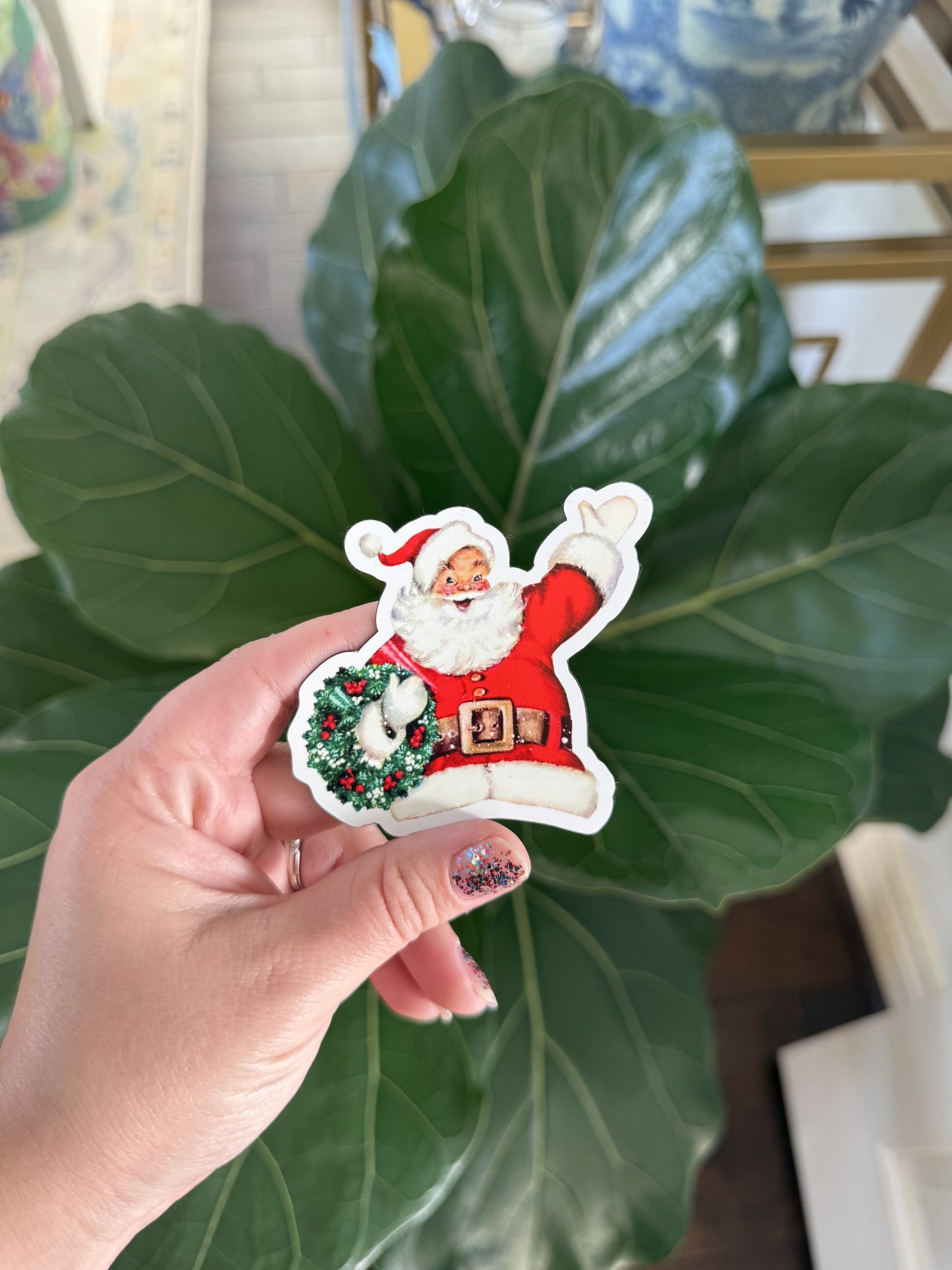 A magnet of a Santa waving and holding a wreath