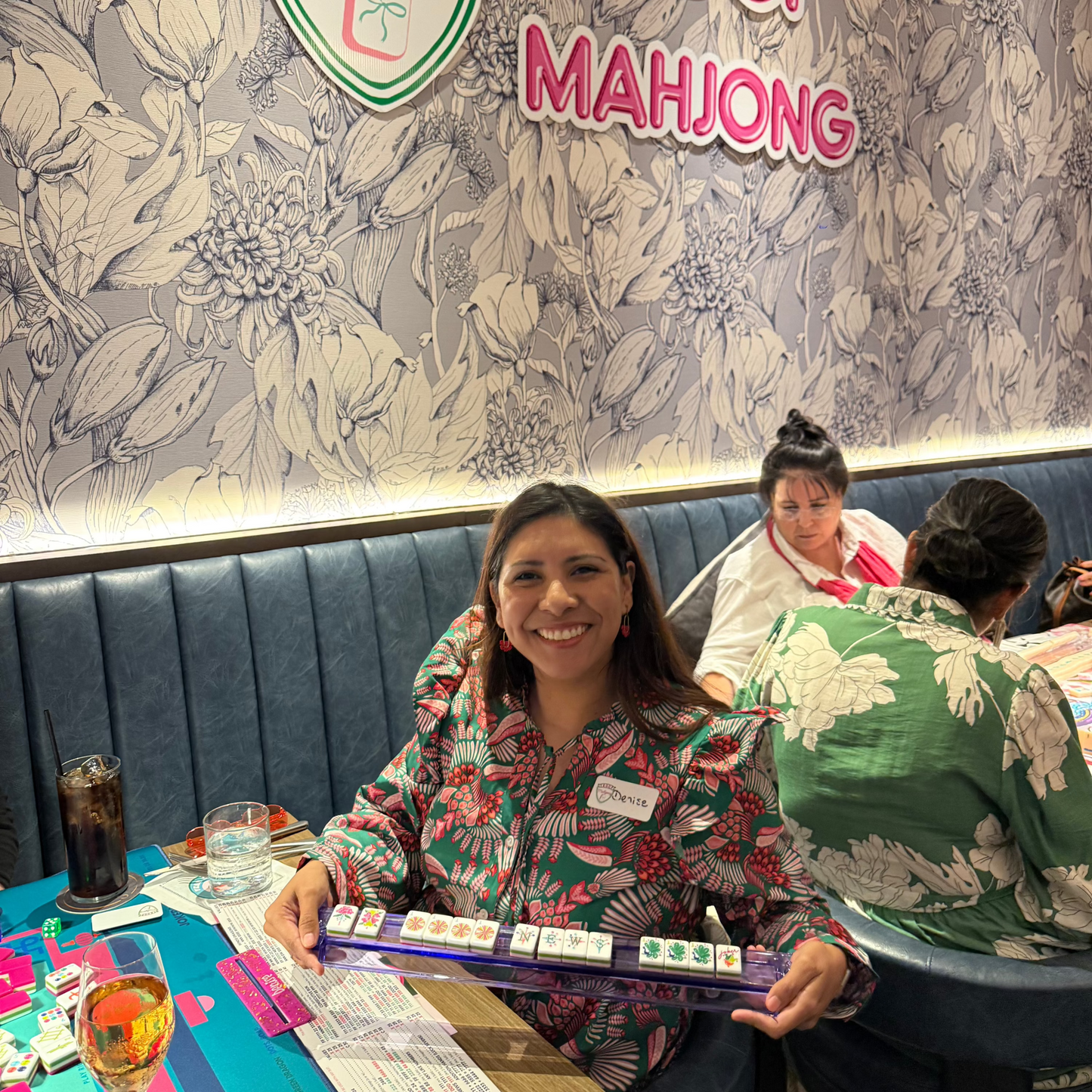 Troop Mahjong member holding a mahjong rack with tiles arranged in a winning hand, or mahjong.