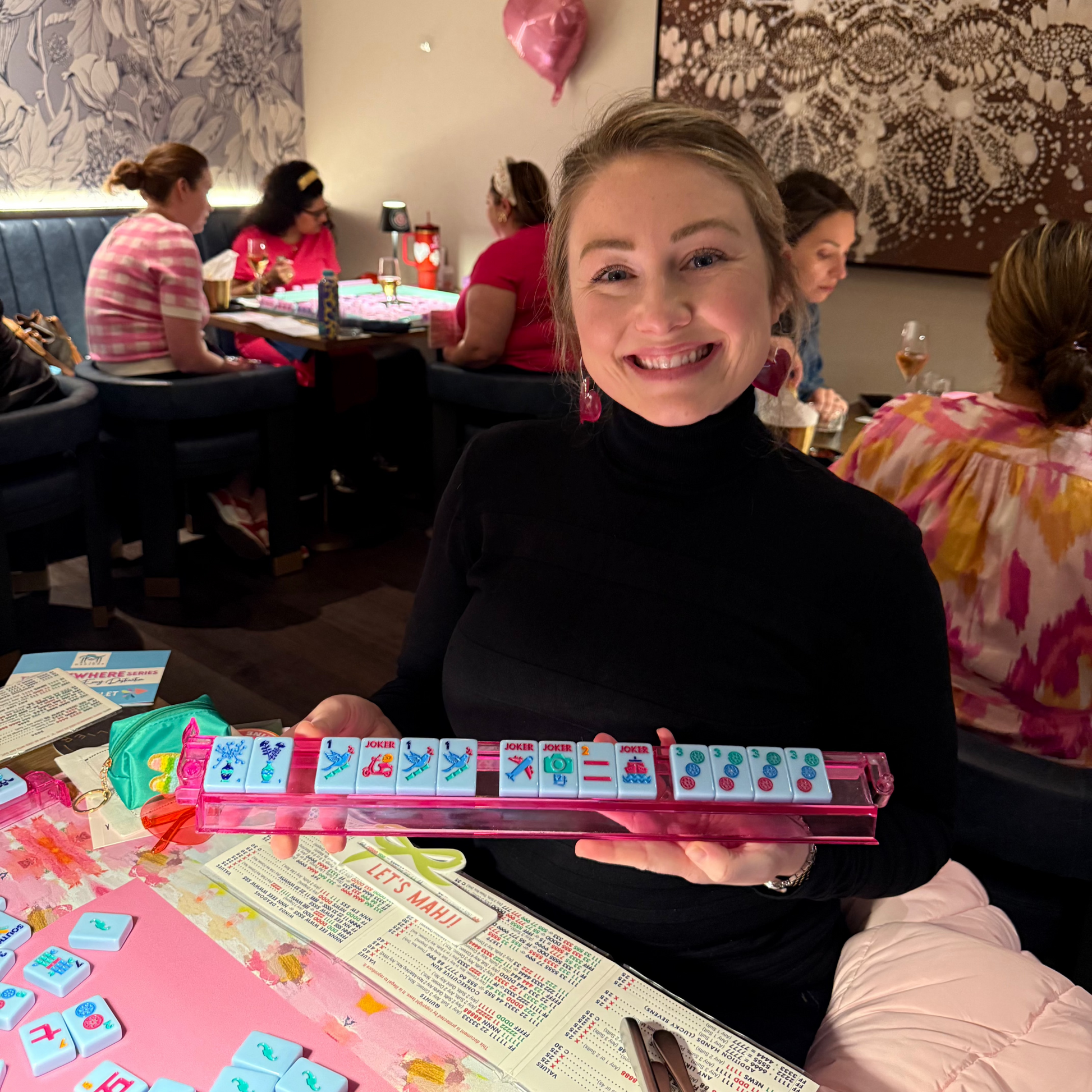 Troop Mahjong member holding a mahjong rack with tiles arranged in a winning hand, or mahjong.