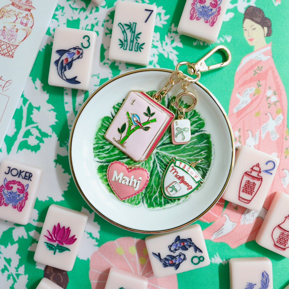 Keychain with Mahjong-themed charms on a green background with Mahjong tiles.